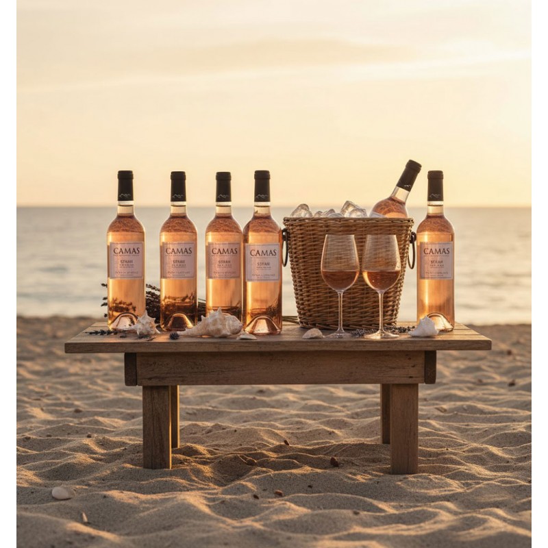 Six bouteilles de vin rosé Camas Syrah Anne de Joyeuse sur une table en bois au coucher du soleil, plage et panier en osier rempli de glace
